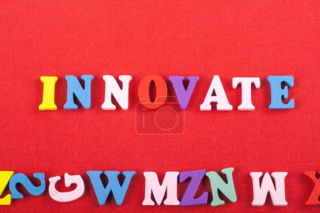INNOVATE word on red background composed from colorful abc alphabet block wooden letters, copy space for ad text. Learning english concept