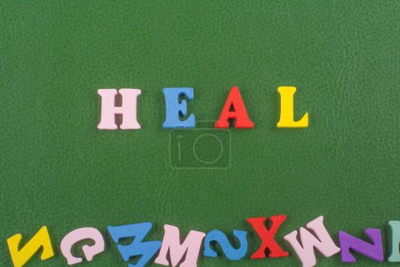 HEAL word on green background composed from colorful abc alphabet block wooden letters, copy space for ad text. Learning english concept