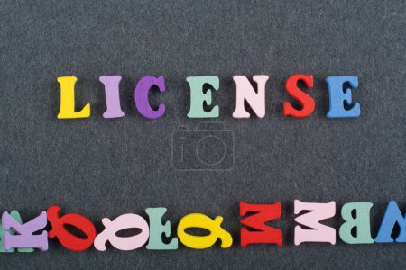 Lizenzwort auf schwarzem Hintergrund, bestehend aus bunten Abc-Buchstaben-Block-Holzbuchstaben, Kopierfläche für Anzeigentext. Englischlerndes Konzept