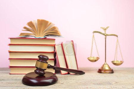 Rechtskonzept - Offenes Gesetzbuch, Richtergabel, Waage, Themis Statue auf dem Tisch im Gerichtssaal oder in der Strafverfolgungsbehörde. Holztisch, rosa Hintergrund.