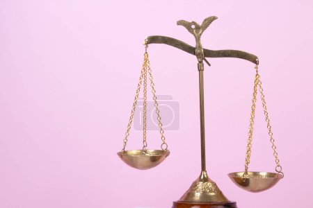 Rechtskonzept - Offenes Gesetzbuch, Richtergabel, Waage, Themis Statue auf dem Tisch im Gerichtssaal oder in der Strafverfolgungsbehörde. Holztisch, rosa Hintergrund