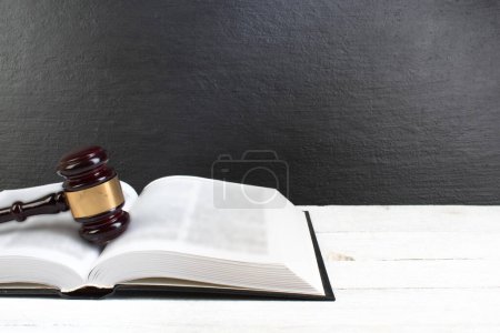 Photo for Law concept - Open law book with a wooden judges gavel on table in a courtroom or law enforcement office isolated on white table. Copy space for text - Royalty Free Image