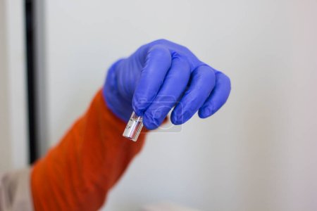 Photo for A hand in a rubber glove holding a vial close-up. - Royalty Free Image