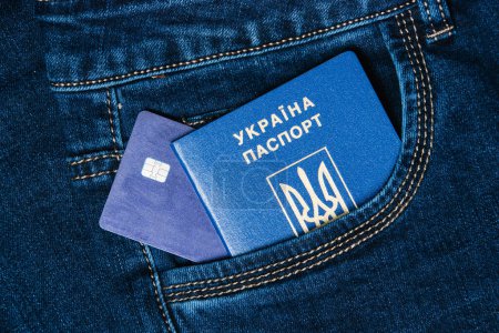Foto de Tarjeta bancaria y pasaporte extranjero de un ciudadano de Ucrania en un bolsillo vaquero. Concepto de refugiados durante la guerra. El concepto de pagos en efectivo a los refugiados. - Imagen libre de derechos