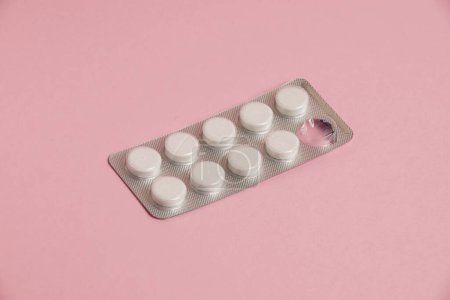 Photo for White pills in a blister on a pink paper background. Concept of treatment of diseases and support of the body in spring. - Royalty Free Image