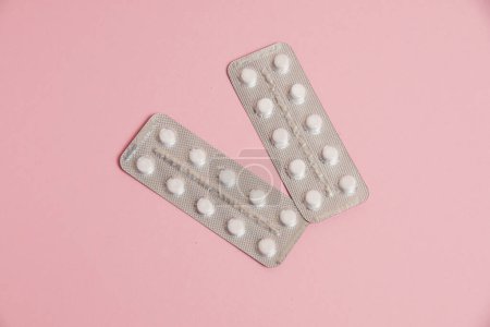 Photo for White pills in a blister on a pink paper background. Concept of treatment of diseases and support of the body in spring. - Royalty Free Image