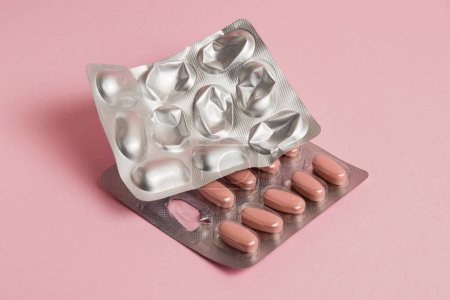 Photo for Pills in a gray blister on a pink paper background. Concept of treatment of diseases and support of the body in spring. - Royalty Free Image