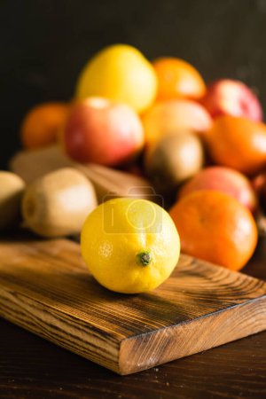 Téléchargez les photos : Fruits dans un sac réutilisable. Jour de la Terre et concept zéro déchet. Orange, citron macro, pomme, kiwi, grenade et planche à découper en bois sur fond sombre. - en image libre de droit