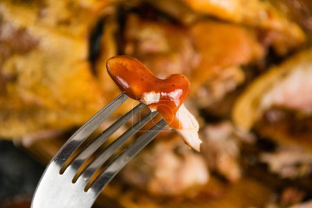 Photo for Appetizing piece of baked pork in tomato sauce on a fork. - Royalty Free Image