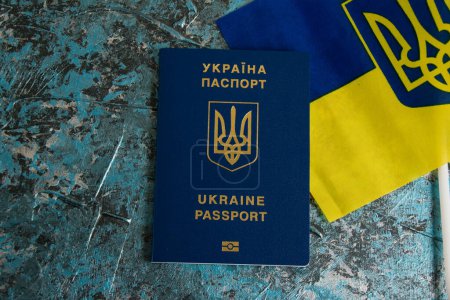 Bandera de Ucrania con escudo de armas y pasaporte extranjero sobre un fondo oscuro. Salida de ucranianos al extranjero o estancia de ciudadanos de Ucrania fuera del país en relación con la guerra con Rusia