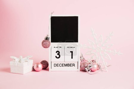 Foto de Año Nuevo, calendario de madera con la fecha 31 de diciembre y decoraciones del árbol de Navidad sobre un fondo rosa. Concepto de celebración de Navidad y Año Nuevo - Imagen libre de derechos