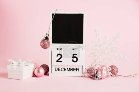 Foto de Navidad, calendario de madera con fecha 25 de diciembre y decoraciones de árboles de Navidad sobre fondo rosa. Concepto de celebración de Navidad y Año Nuevo - Imagen libre de derechos