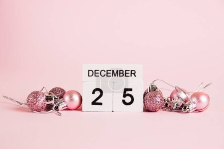 Foto de Navidad, calendario de madera con fecha 25 de diciembre y decoraciones de árboles de Navidad sobre fondo rosa. Concepto de celebración de Navidad y Año Nuevo - Imagen libre de derechos