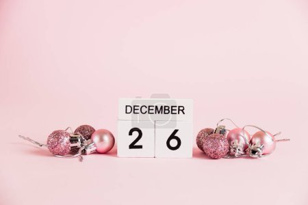 Foto de Navidad y Boxeo, calendario de madera con fecha 26 de diciembre y decoraciones de árboles de Navidad sobre fondo rosa. Concepto de celebración de Navidad y Año Nuevo - Imagen libre de derechos