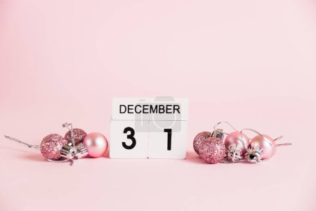 Foto de Año Nuevo, calendario de madera con la fecha 31 de diciembre y decoraciones del árbol de Navidad sobre un fondo rosa. Concepto de celebración de Navidad y Año Nuevo - Imagen libre de derechos