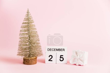 Foto de Decoración navideña y calendario con fecha 25 de diciembre sobre papel rosa con espacio para copiar. Concepto de celebración de Navidad y Año Nuevo - Imagen libre de derechos