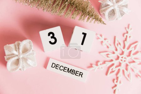 Foto de Flatlay, decoración navideña y calendario con fecha 31 de diciembre sobre fondo de papel rosa con espacio para copiar, Año Nuevo. Concepto de celebración de Navidad y Año Nuevo - Imagen libre de derechos