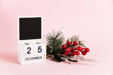 Foto de Rama y calendario de árbol de decoración navideña con fecha 25 de diciembre sobre papel rosa con espacio para copiar. Concepto de celebración de Navidad y Año Nuevo - Imagen libre de derechos
