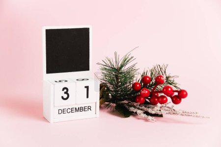 Foto de Árbol de Navidad decoración de ramas y calendario con fecha 31 de diciembre sobre fondo de papel rosa con espacio para copiar. Concepto de celebración de Navidad y Año Nuevo - Imagen libre de derechos