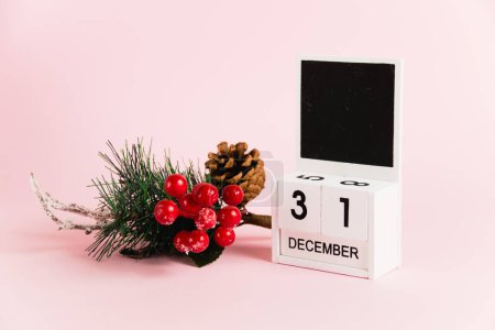 Foto de Árbol de Navidad decoración de ramas y calendario con fecha 31 de diciembre sobre fondo de papel rosa con espacio para copiar. Concepto de celebración de Navidad y Año Nuevo - Imagen libre de derechos