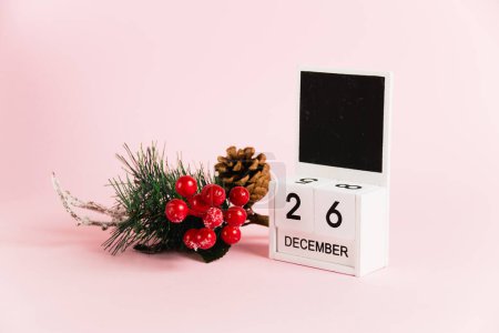 Foto de Rama de árbol de decoración de Navidad y calendario con fecha 26 de diciembre en papel rosa con espacio para copiar. Concepto de celebración de Navidad y Año Nuevo - Imagen libre de derechos