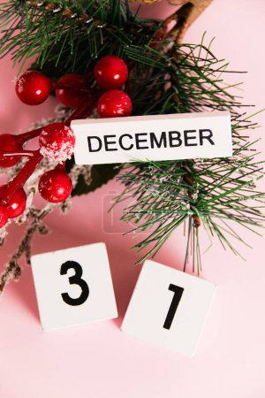 Foto de Flatlay, decoración de ramas de árbol de Navidad y calendario con fecha 31 de diciembre sobre fondo de papel rosa con espacio para copiar. Concepto de celebración de Navidad y Año Nuevo. - Imagen libre de derechos