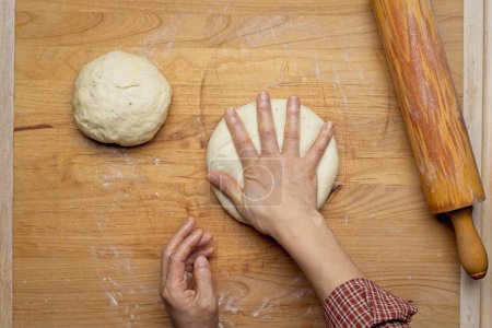 Foto de A flatlay photo of patting a small ball of dough down to get it ready to roll out using the rolling pin. - Imagen libre de derechos