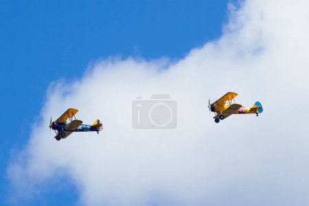 Two old style biplanes flying in formation in the bright sky near Liberty Lake, Washington.