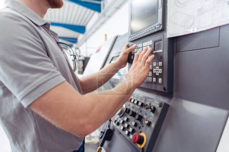 Fertigungsarbeiter programmieren industrielle CNC-Werkzeugmaschinen während der Eingabe von Arbeitsdaten