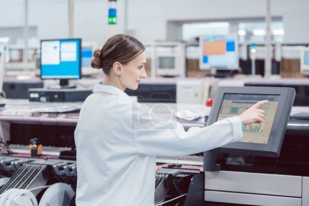 Foto de Mujer en control compute de línea de montaje en fábrica de electrónica - Imagen libre de derechos