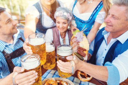 Photo for Group of friends toasting in Bavarian beer garden - Royalty Free Image