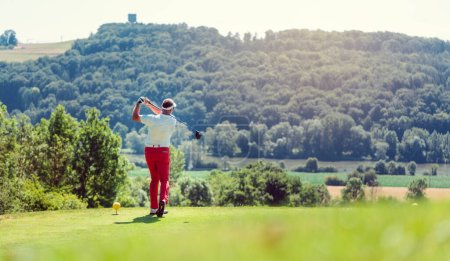 Photo for Golf player hitting ball long with driver, wide shot - Royalty Free Image