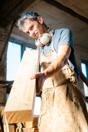 Foto de Hombre carpintero en su taller eligiendo madera para el próximo proyecto - Imagen libre de derechos