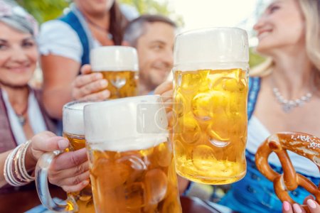 Gruppe klingelt mit Bier im bayerischen Biergarten