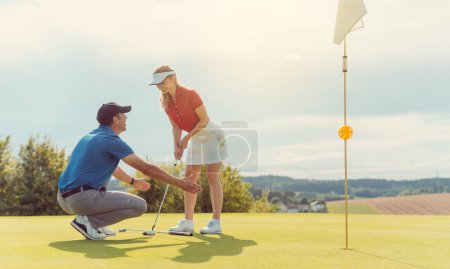 Téléchargez les photos : Pro sur le terrain de golf enseigner à une femme comment mettre, gros plan - en image libre de droit