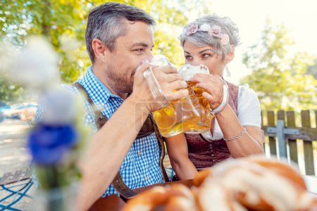 Téléchargez les photos : Couple d'âge mûr buvant dans le jardin de bière bavarois - en image libre de droit