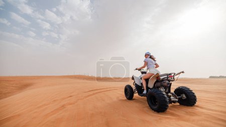 Téléchargez les photos : Femme chevauchant des dunes de sable VTT dans le désert de Dubaï - en image libre de droit