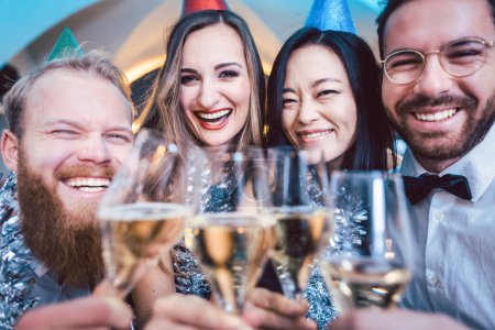 Foto de Grupo de amigos en un bar brindando con champán y celebrando cumpleaños o víspera de año nuevo - Imagen libre de derechos