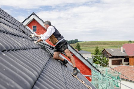 Foto de Roofer trabajando en el techo de una casa privada, disparado en gran angular sobre las baldosas - Imagen libre de derechos