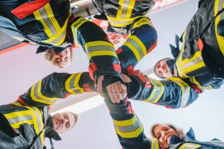 Téléchargez les photos : Pompiers hommes et femmes faisant quelques teambuilding empilant les mains - en image libre de droit