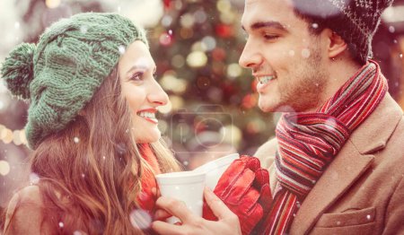 Photo for Couple, man and woman, on a christmas market in winter drinking hot spiced wine, looking at each other with love - Royalty Free Image