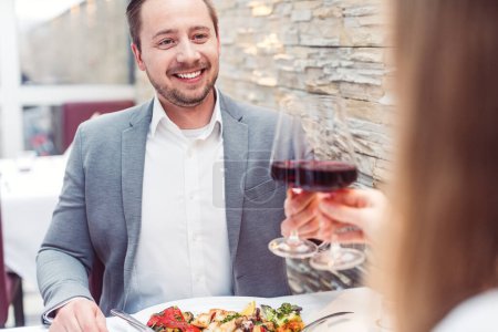 Photo for Man and woman enjoying a glass of red wine with their meal having a great time - Royalty Free Image