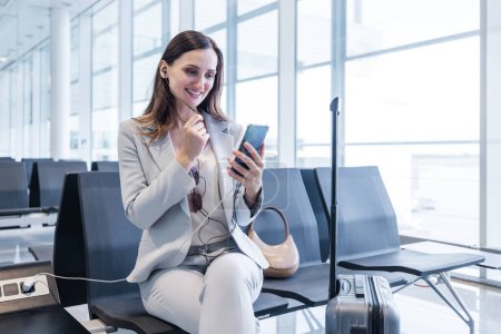 Téléchargez les photos : Femme d'affaires faisant quelques appels liés au travail rapide en attendant l'enregistrement à la porte de l'aéroport - en image libre de droit