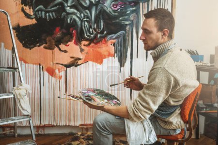 Téléchargez les photos : Artiste professionnel tenant palette et pinceau pour dessiner la peinture sur mur, en atelier d'art - en image libre de droit