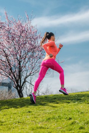 Photo for Woman running on hill for fitness as a sport in front of city - Royalty Free Image