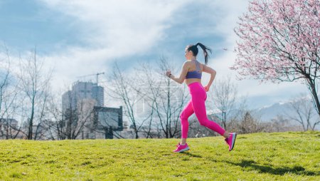 Photo for Sportive girl running in park on spring day in front of blossom - Royalty Free Image