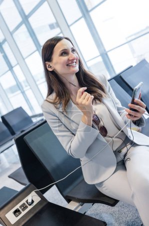 Téléchargez les photos : Femme d'affaires faisant quelques appels liés au travail rapide en attendant l'enregistrement à la porte de l'aéroport - en image libre de droit