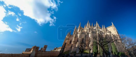 Foto de La Catedral de Segovia se erige como un icono monumental de la arquitectura gótica, mostrando siglos de historia y arte en su intrincada piedra y sus imponentes agujas. La elegancia de la fachada detallada, combinada con la grandeza de su majestuoso str - Imagen libre de derechos