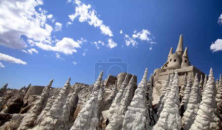 Photo for A castle sculpted from sand stands proudly on the beach, a temporary monument to seaside creativity. Above, the sky stretches out in a vast expanse of intense azure, its clear, blue canvas contrasting vividly with the intricate granularity of the san - Royalty Free Image