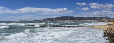 Téléchargez les photos : Vue panoramique sur la plage de Palma avec les eaux turquoise de la Méditerranée et la cathédrale La Seu sous un ciel nuageux - en image libre de droit